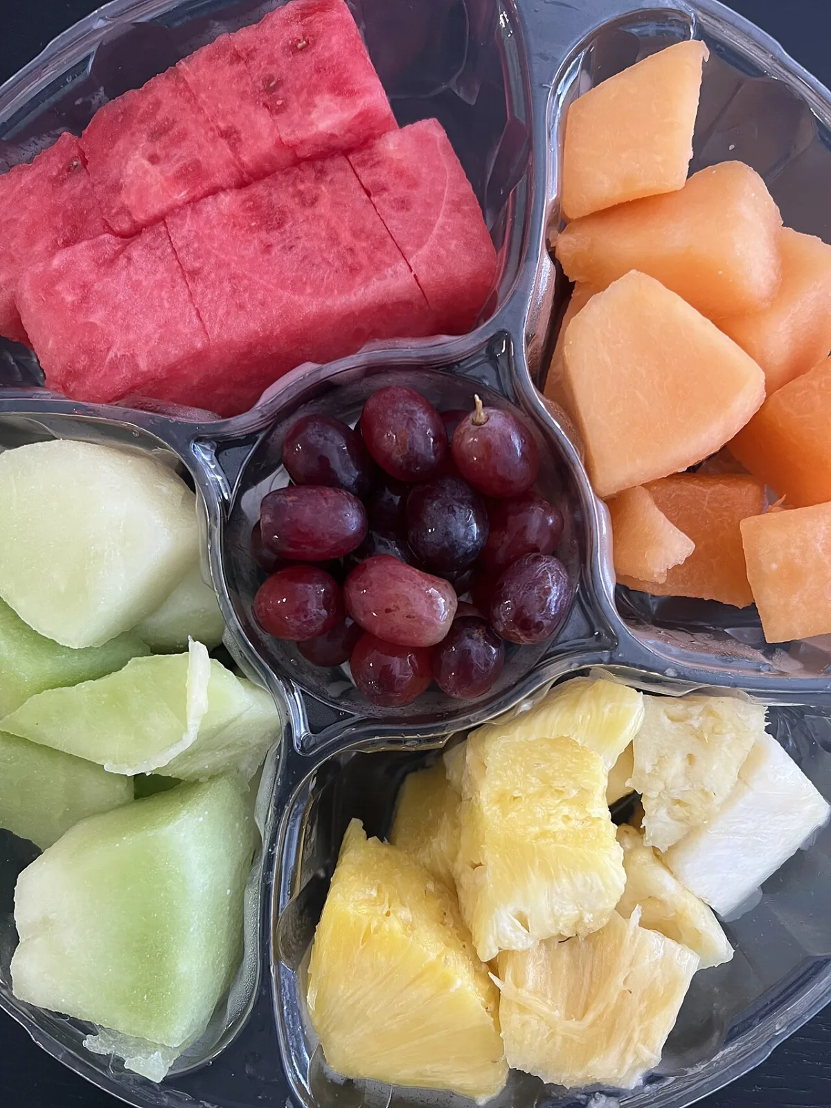 Verdeeld schaaltje met watermeloen, meloen, druiven en ananas, fruit met uiteenlopende glycemische index.