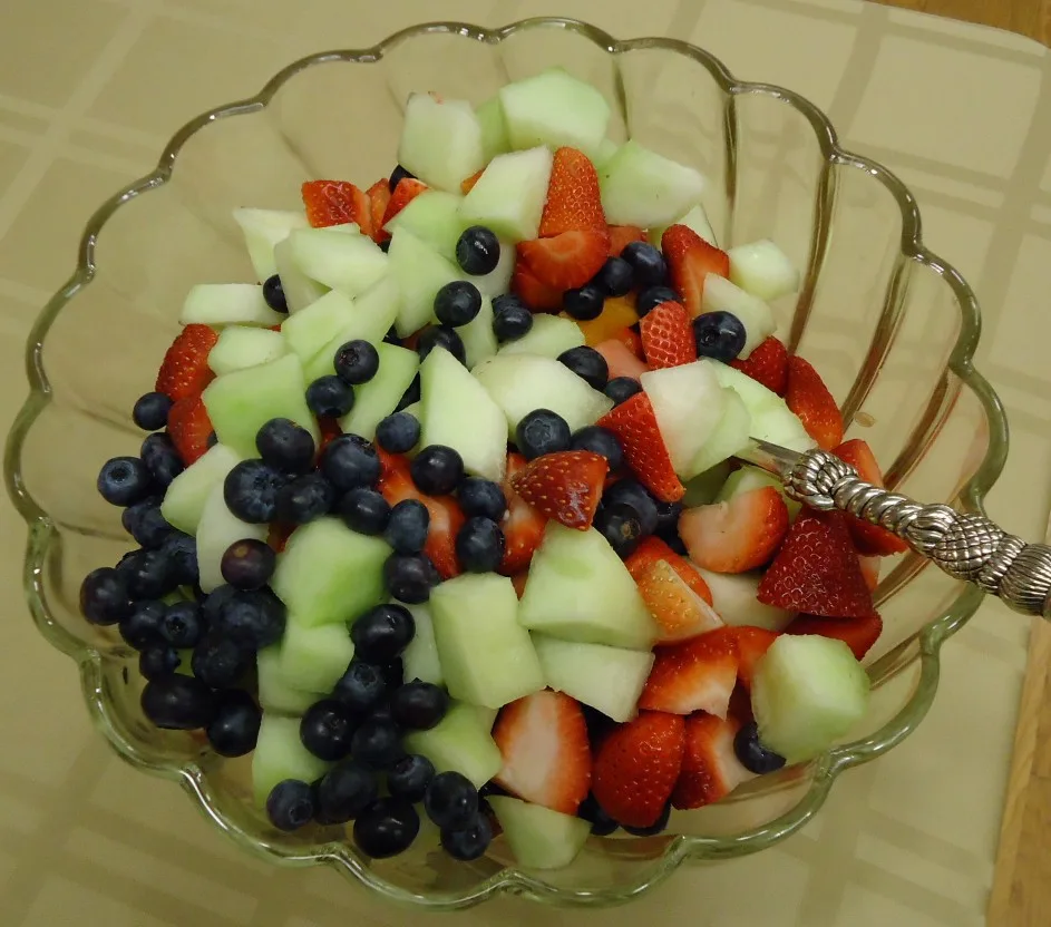 Glazen kom met honingmeloen, blauwe bessen en aardbeien, laagcalorisch fruit voor bij afvallen.