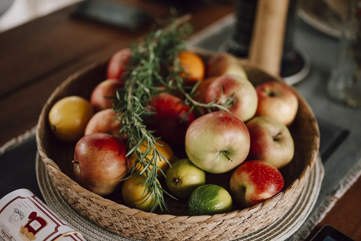 Schaal met verse appels, citroenen en limoenen op een tafel.