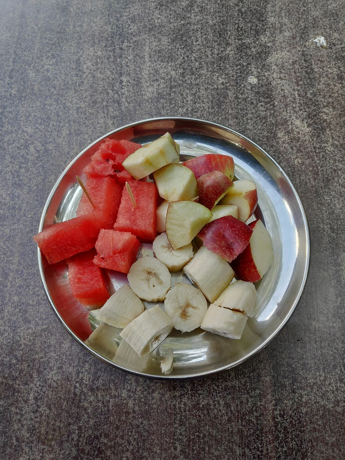 Bord met vers gesneden watermeloen, appel en banaan als vezelrijke fruitsalade.