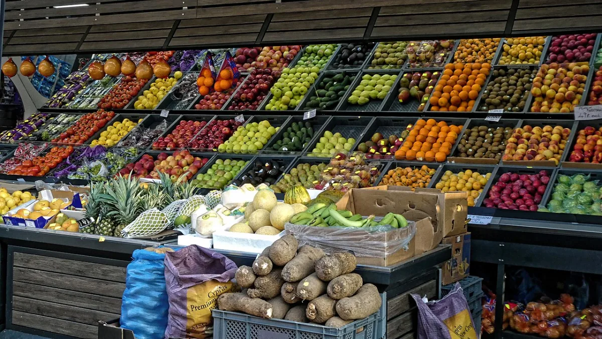 Uitgestald vers fruit in houten kratten bij een groentewinkel, met onder meer appels, citrusvruchten en bananen.