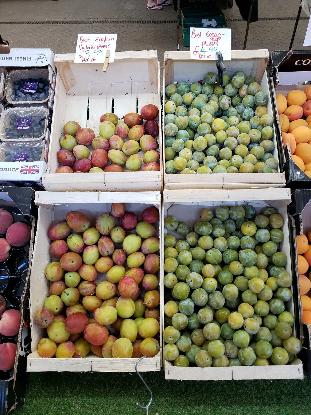 Rijpe pruimen uitgestald in houten kratten op een fruitmarkt.